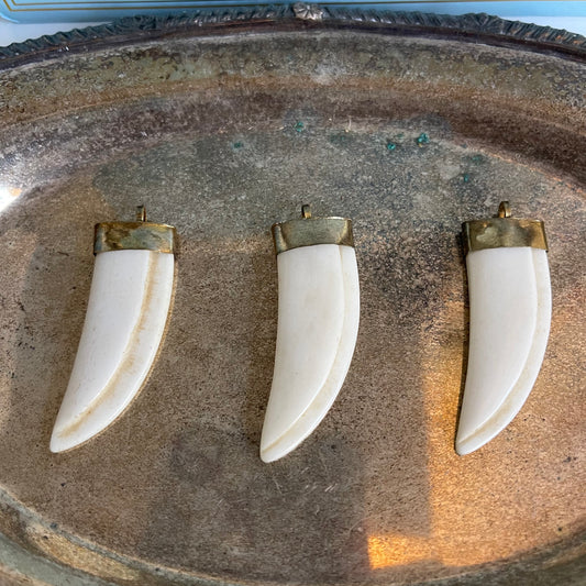 Three bone pendants with brass caps on silver platter