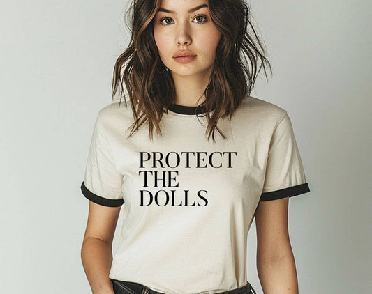 Person wearing an off-white t-shirt with 'PROTECT THE DOLLS' black text on a plain background