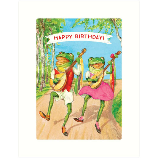 A square greeting card featuring a colorful illustration of two dancing frogs playing stringed instruments on a path, with a white banner reading 'HAPPY BIRTHDAY!' above them.