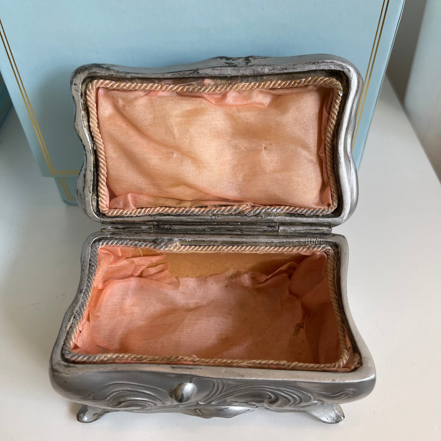Silver jewelry box with pink interior on a white surface
