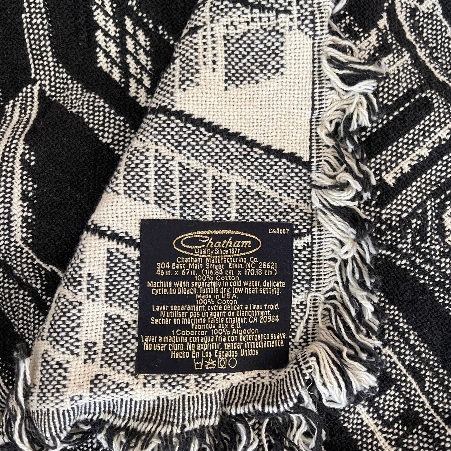 Close-up of a Chatham label on a black and white patterned blanket with fringes.