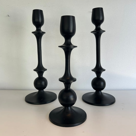 Three black candle holders of different designs on a white background