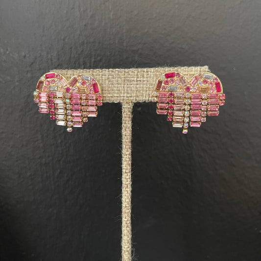 Pair of pink and gold bejeweled heart-shaped earrings on a black background