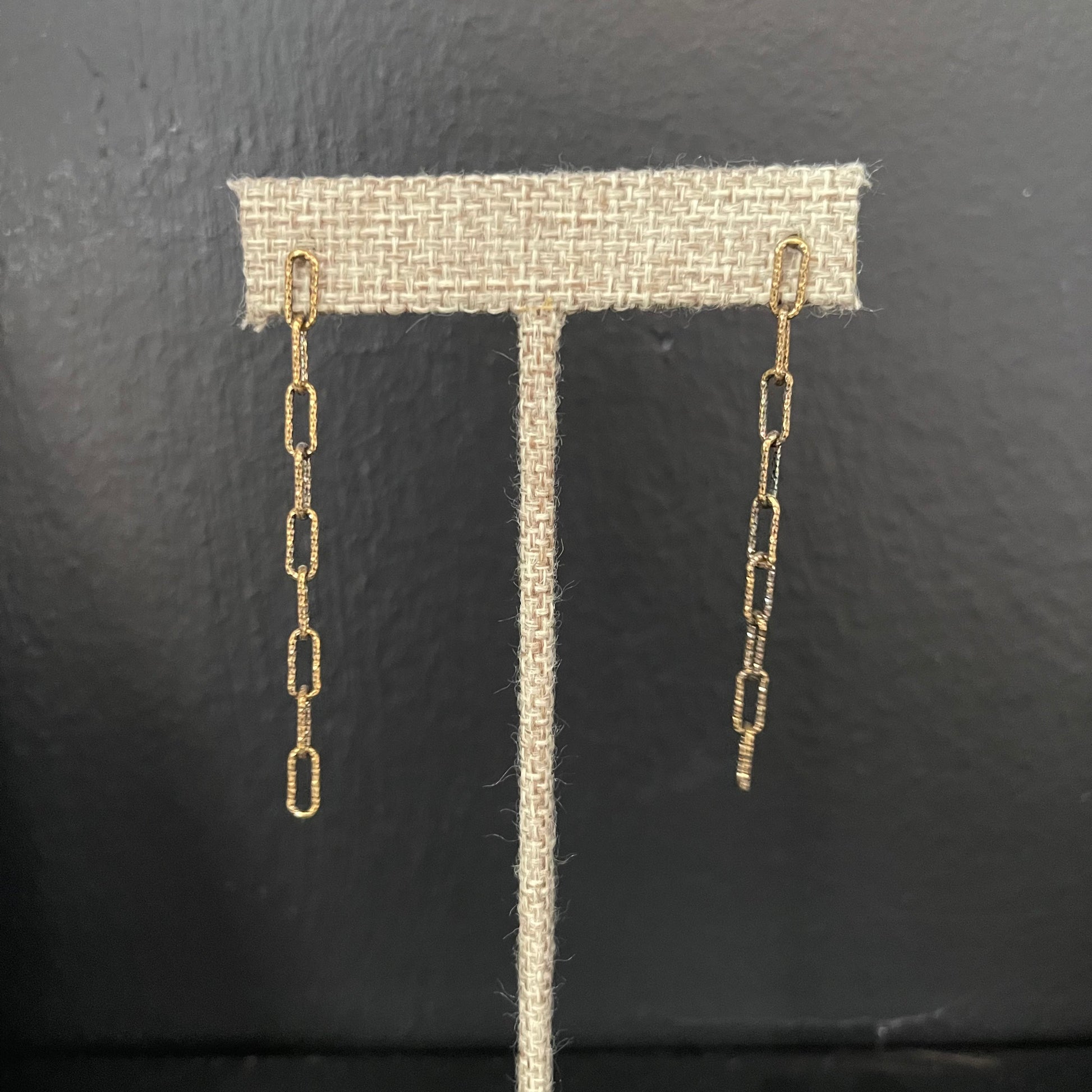 Gold long chain earrings on a black background