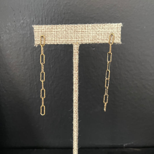 Gold long chain earrings on a black background